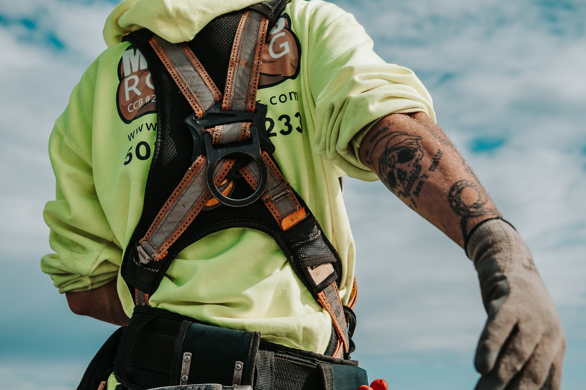 Roofing professional equipped with fall protection and tools for residential roof work. 
