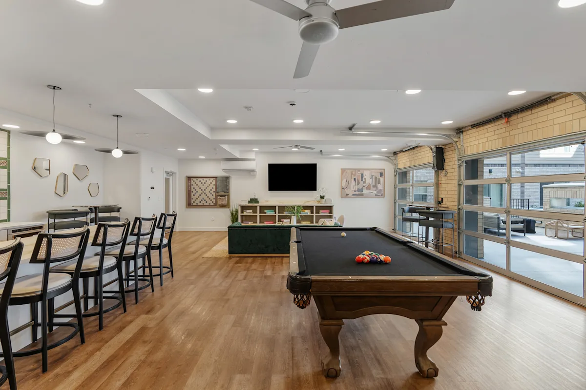 a game room with a pool table and a bar with chairs
