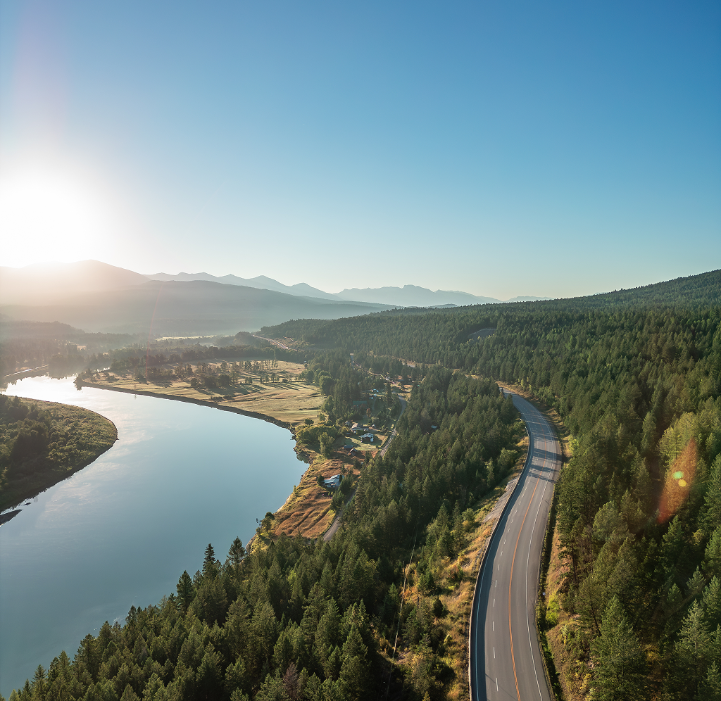 Vue aérienne d’un magnifique paysage avec une route sinueuse et une rivière calme qui le traverse.