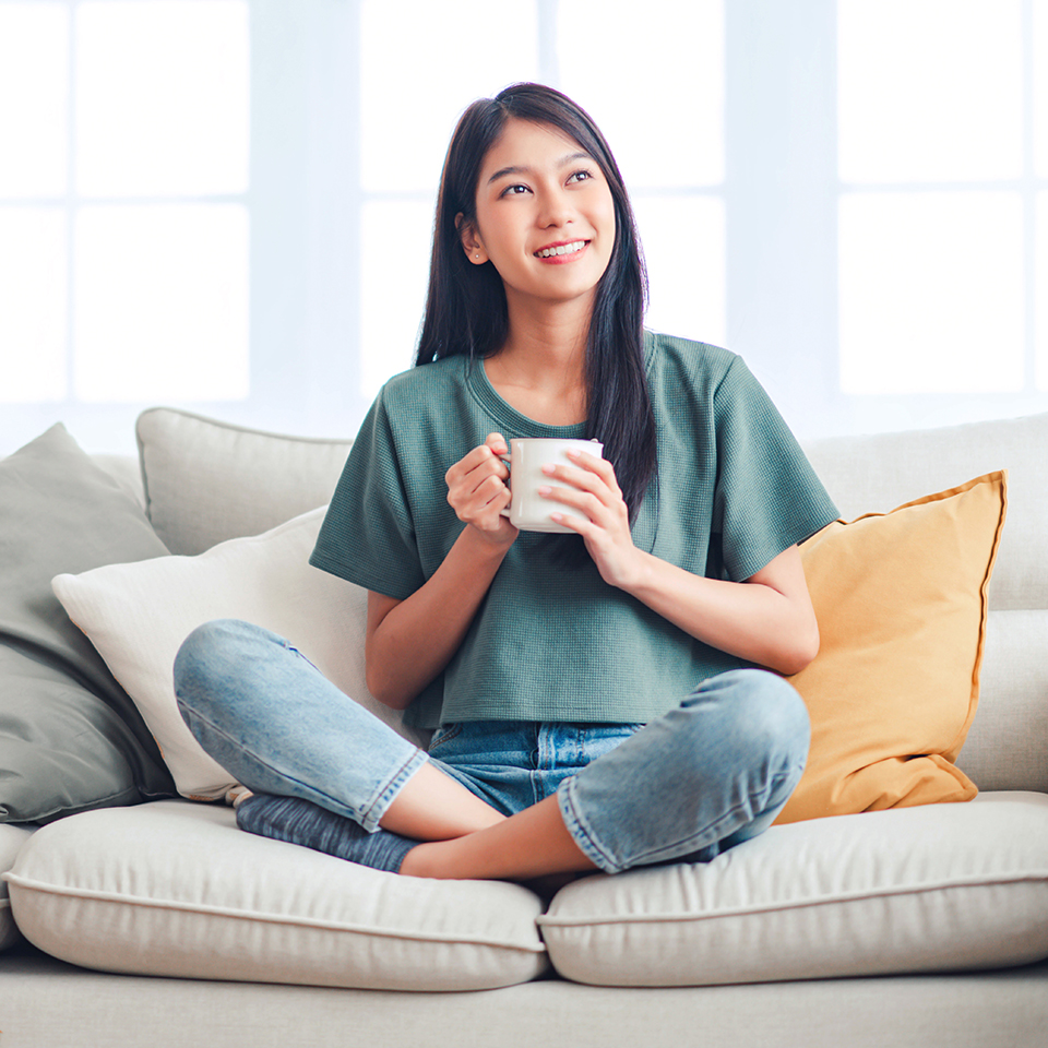 A woman sitting on a couch holding a mug