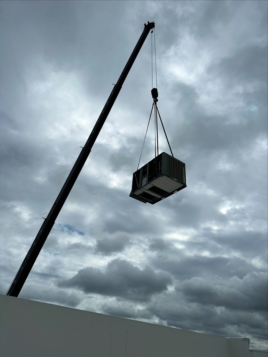 Commercial HVAC unit being crane-lifted onto a rooftop for professional installation and dependable building comfort.