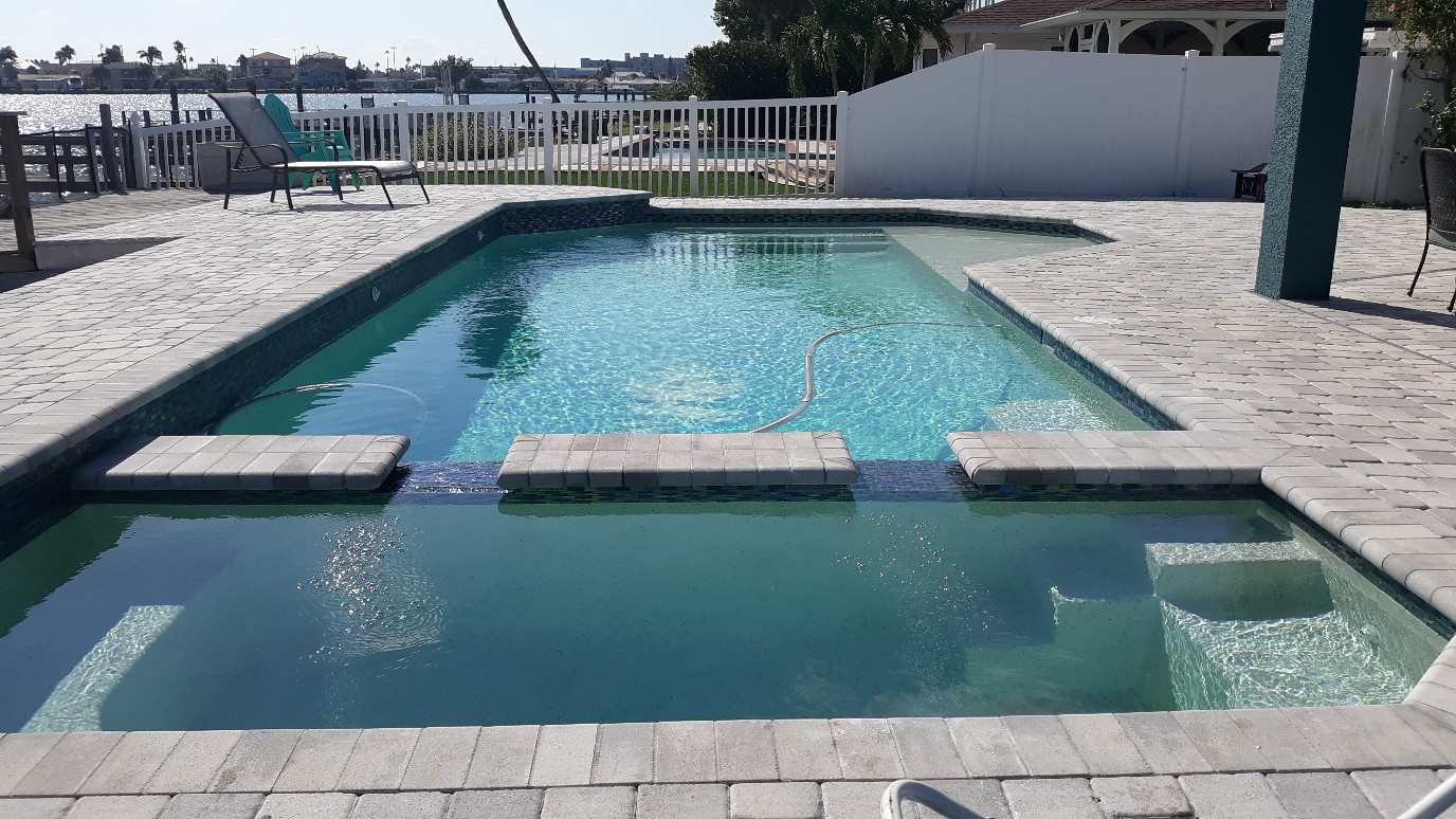Luxury rectangular pool and spa design featuring raised water features, clean lines, and stone paver decking.