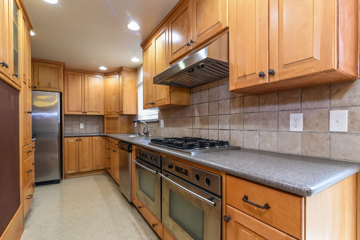 Kitchen with rich wooden cabinets with stainless-steel appliances at Invitation Homes Seattle.