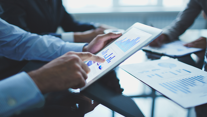 A person pointing at charts on a tablet.