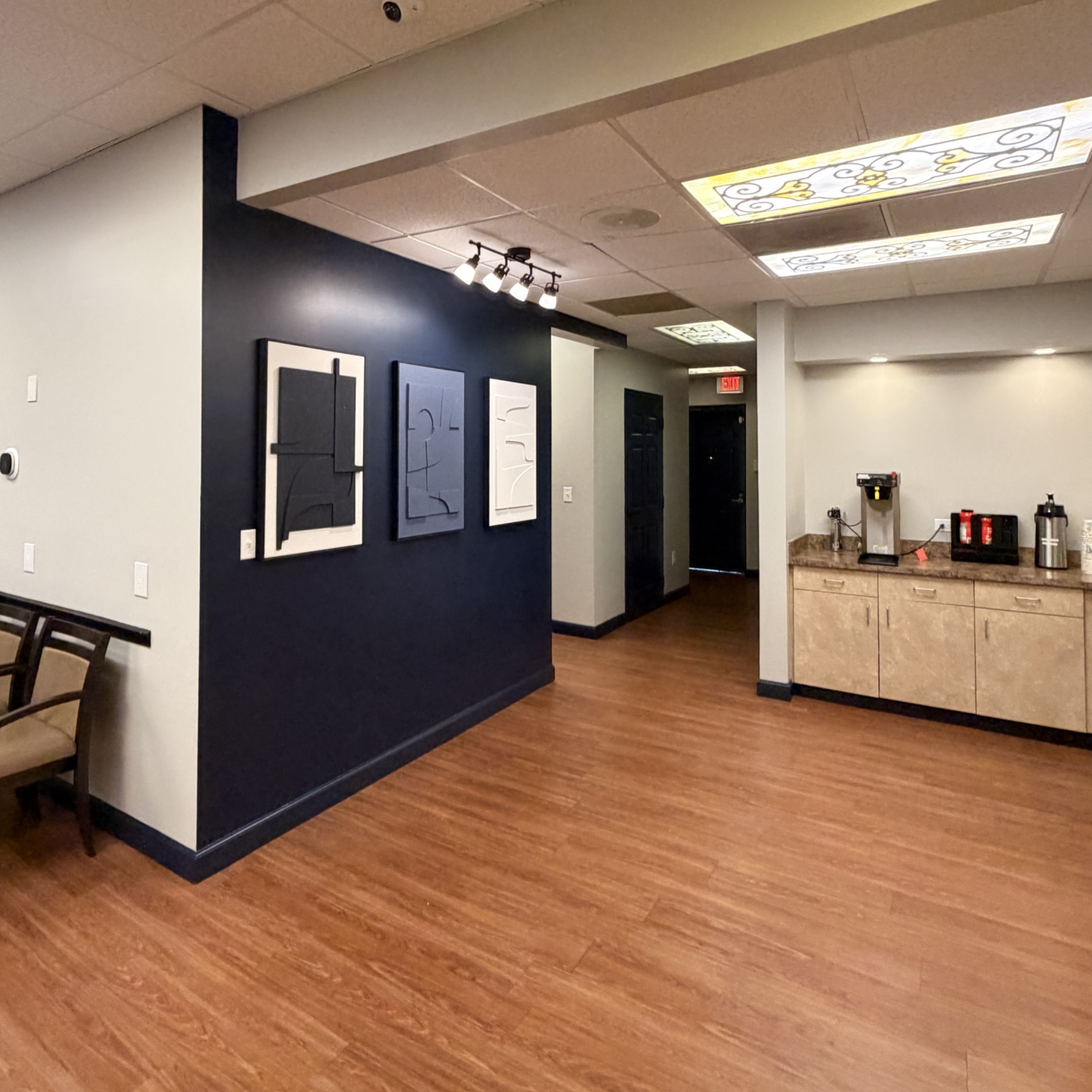 A comfortable corner of our lobby with modern art on our navy accent wall and a coffee bar just arou 