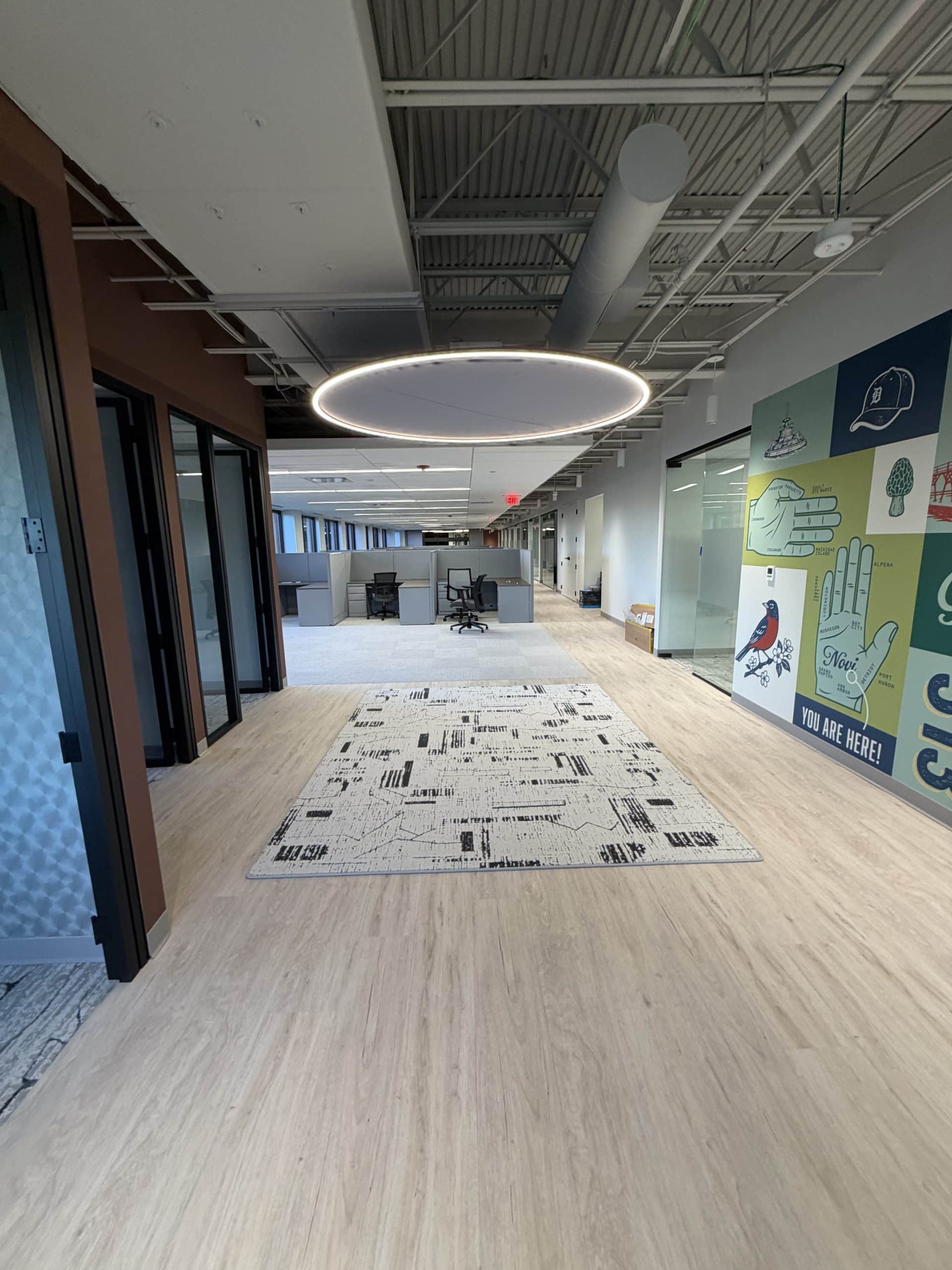 The Toll Brothers Michigan Division Office & Design Studio showcases a contemporary workplace interior within Schonsheck, Inc.’s commercial construction portfolio. Glass-front offices, open workstations, and distinctive lighting create a bright, connected environment, while a colorful Michigan-themed mural adds local character. The space brings together practical office planning and architectural detail to support everyday business operations and present a welcoming professional setting.