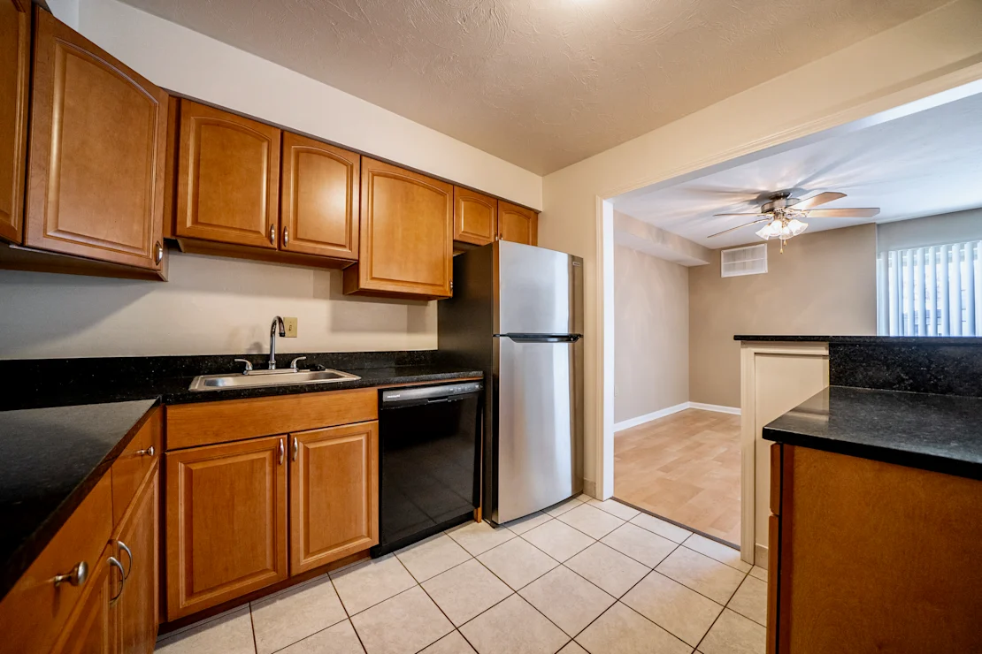 A kitchen with wooden cabinets and a black counter top