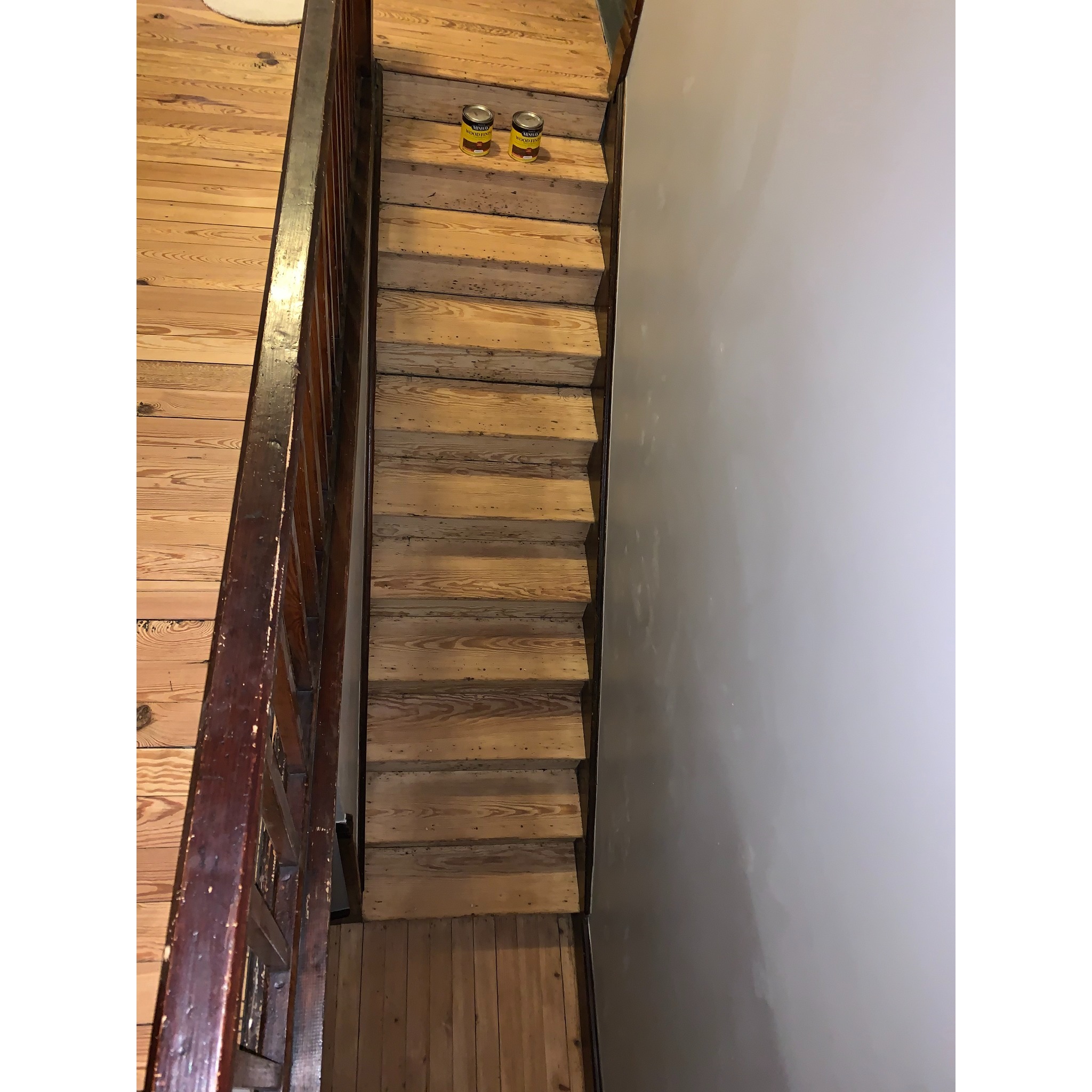 Wooden staircase steps sanded and prepped for staining with Minwax wood finish cans visible - Winona FloorCraft stair refinishing and wood floor staining service.