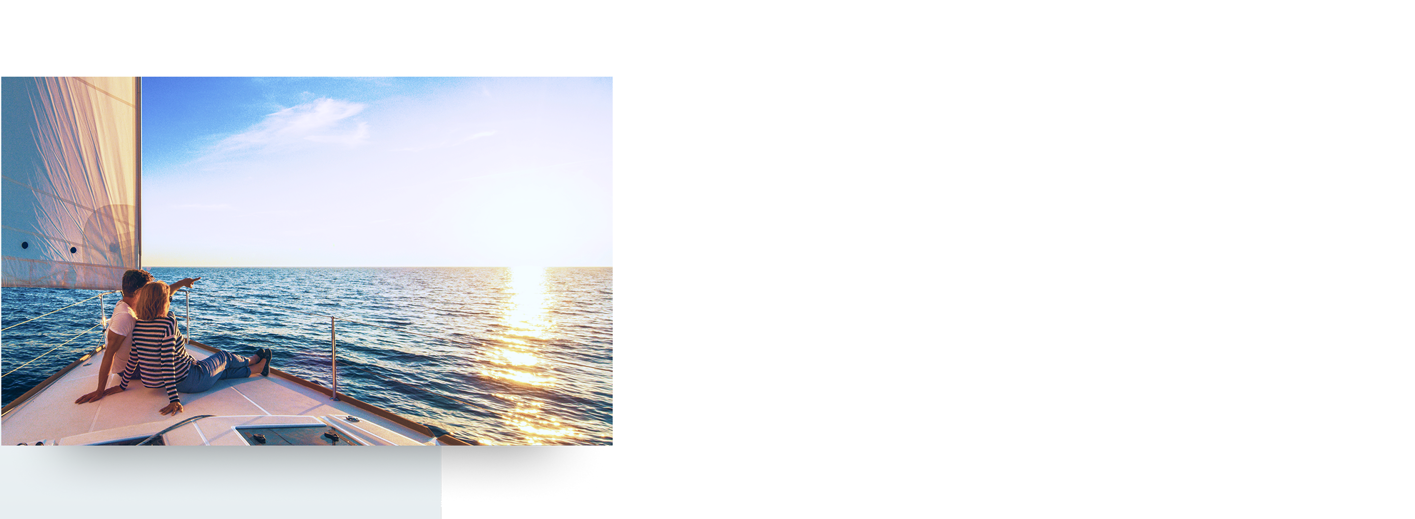 A couple looking out at the ocean from the bow of a sailboat at sunset.