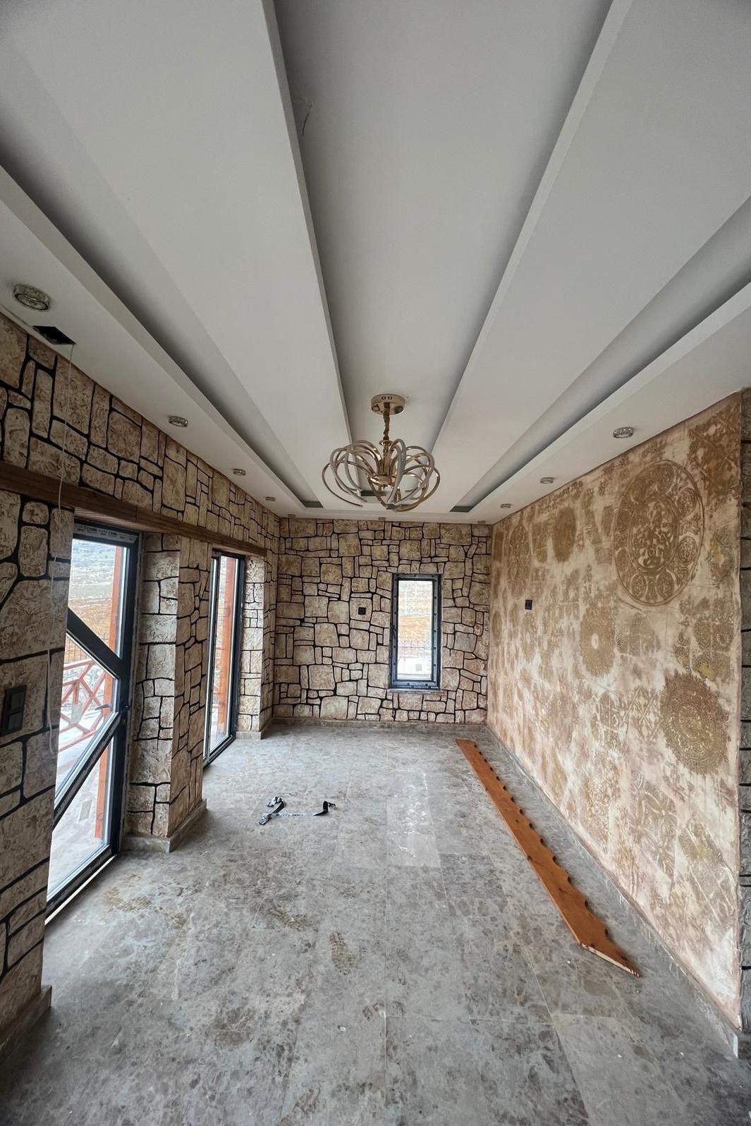This room transformation includes faux-stone paneling, textured art walls, and layered ceiling beams—reflecting a classic-meets-contemporary vibe, ideal for lounges or sunrooms.