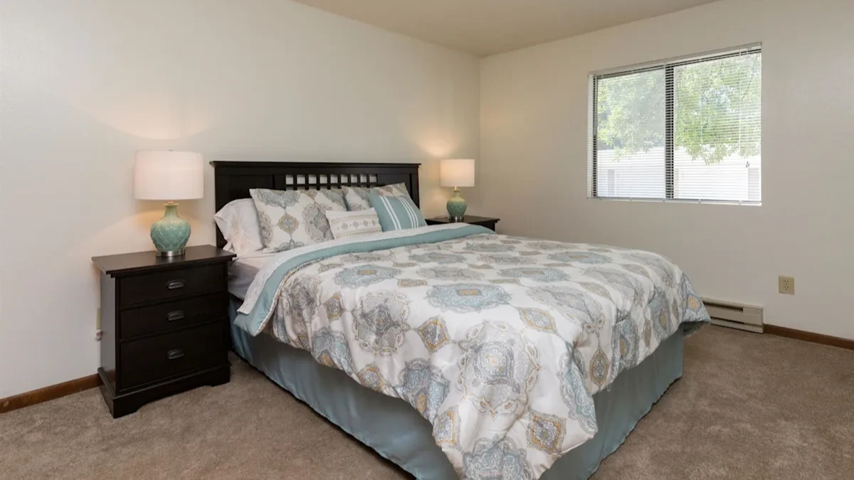 A bedroom with a bed, nightstand, and two lamps