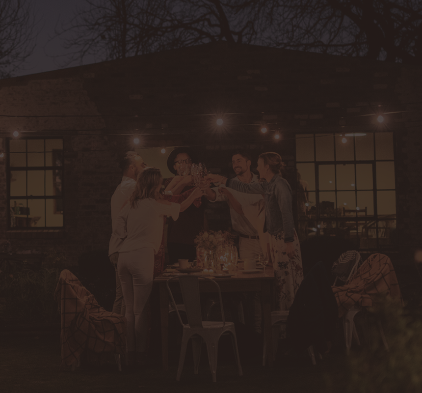 A group of friends celebrating around an outdoor dinner table.