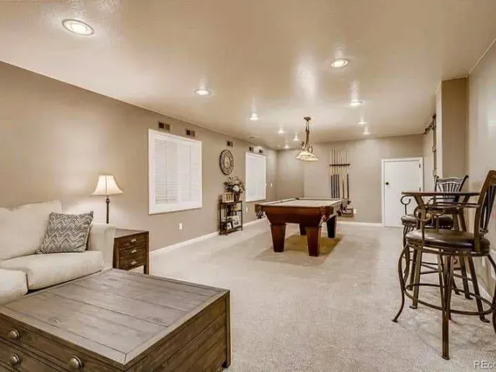 Comfortable basement game room with pool table, seating area, neutral finishes, recessed lighting, and spacious layout, creating an inviting environment for recreation and entertaining guests.