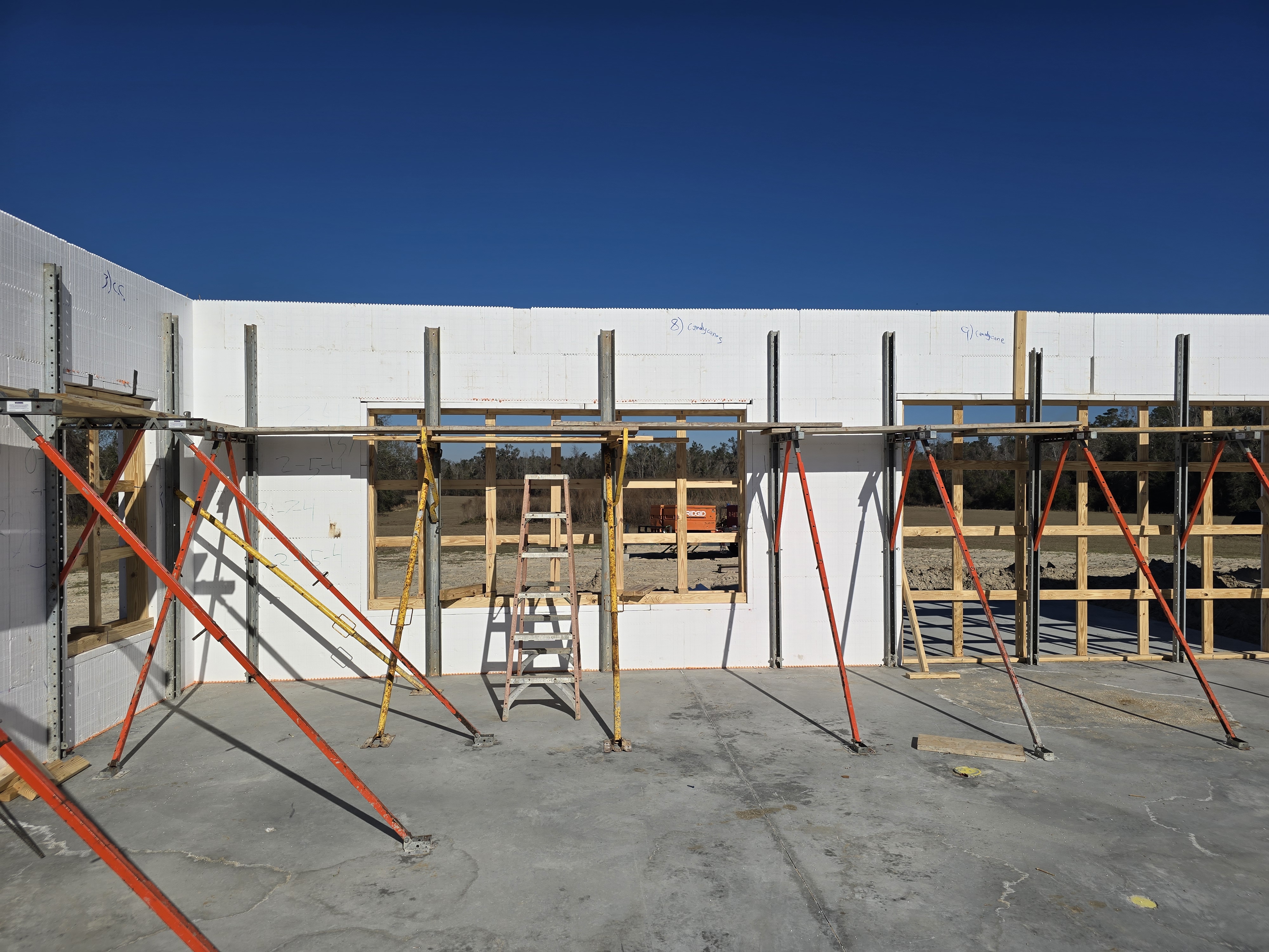 A construction site with the concrete foundation and partially built walls of a building. Scaffoldin 