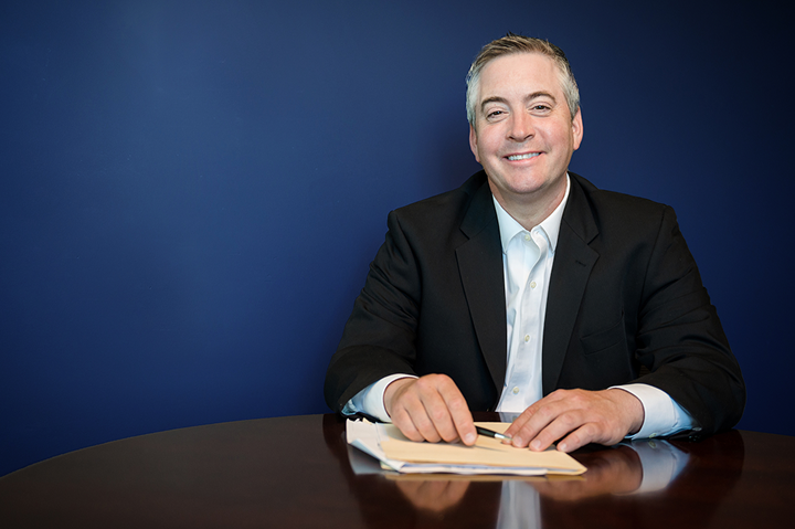 Justin Ginetz at an office table smiling.