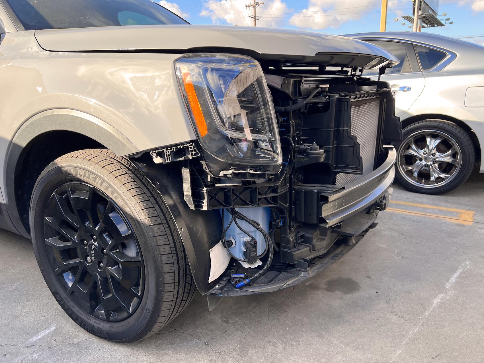 Detailed photo of Kia SUV waiting at auto body shop parking lot for collision repair