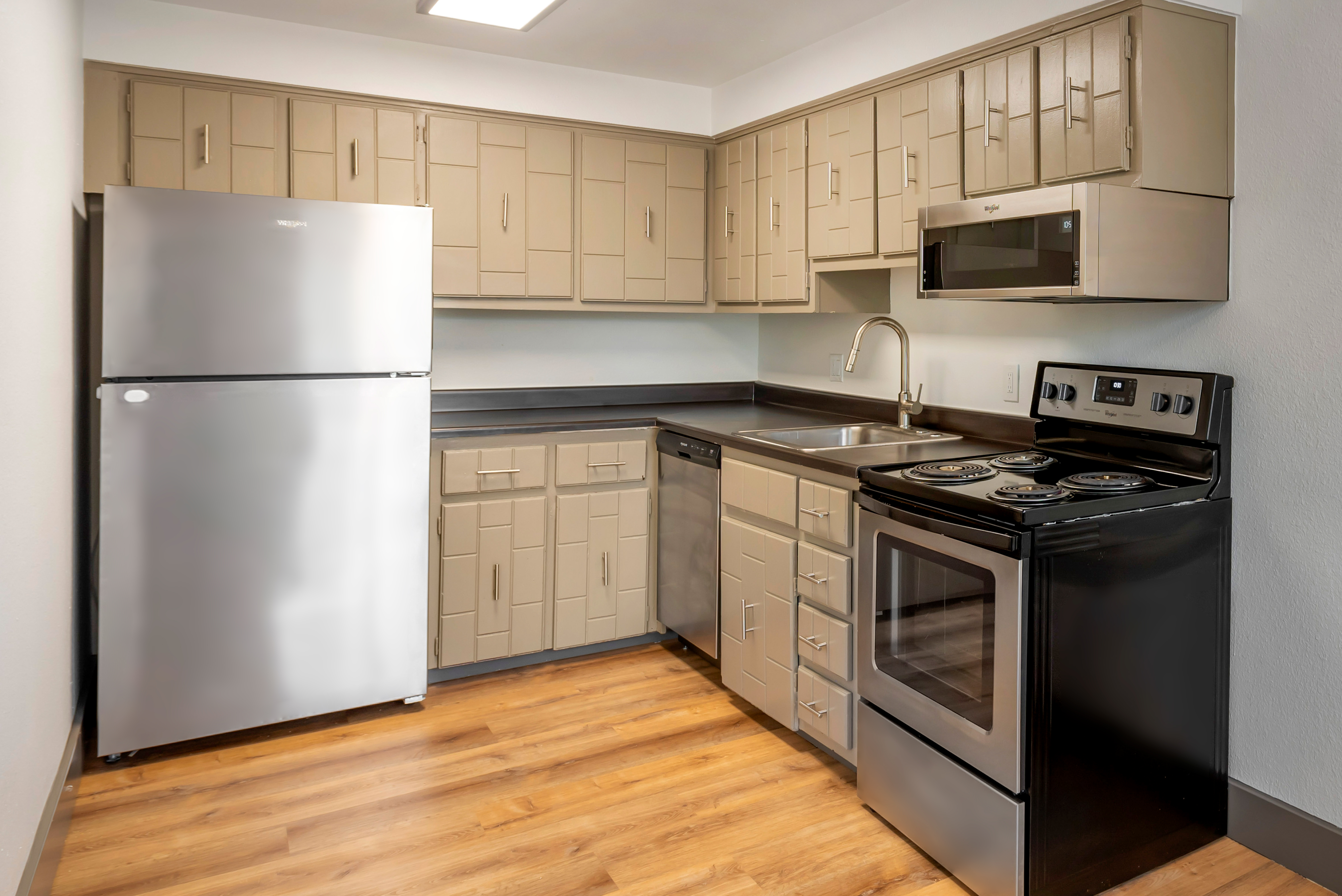 Vinyl floored kitchen with unique brown textured cabinets and stainless steel appliances.