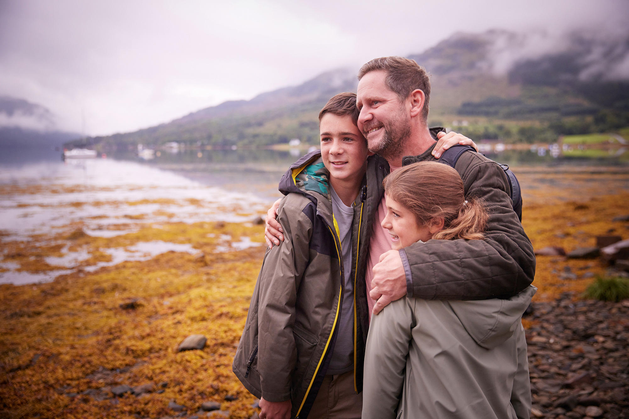 Father hugs his children while out walking the grounds of Drimsynie Estate