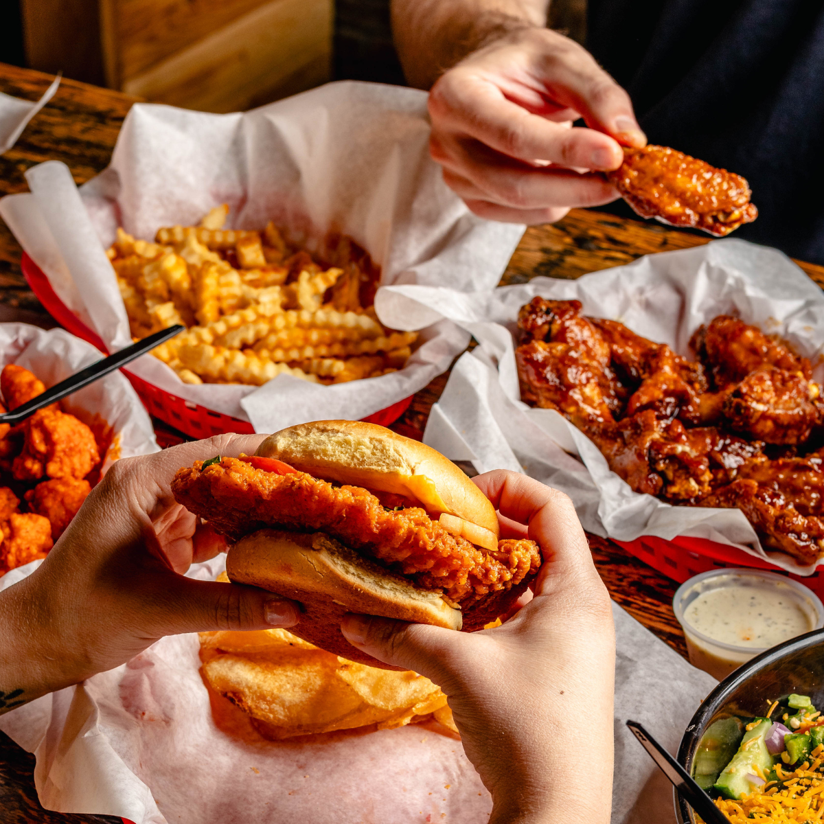 A Buffalo Chicken Sandwich accompanied by crinkle fries, boneless, and traditional wings.