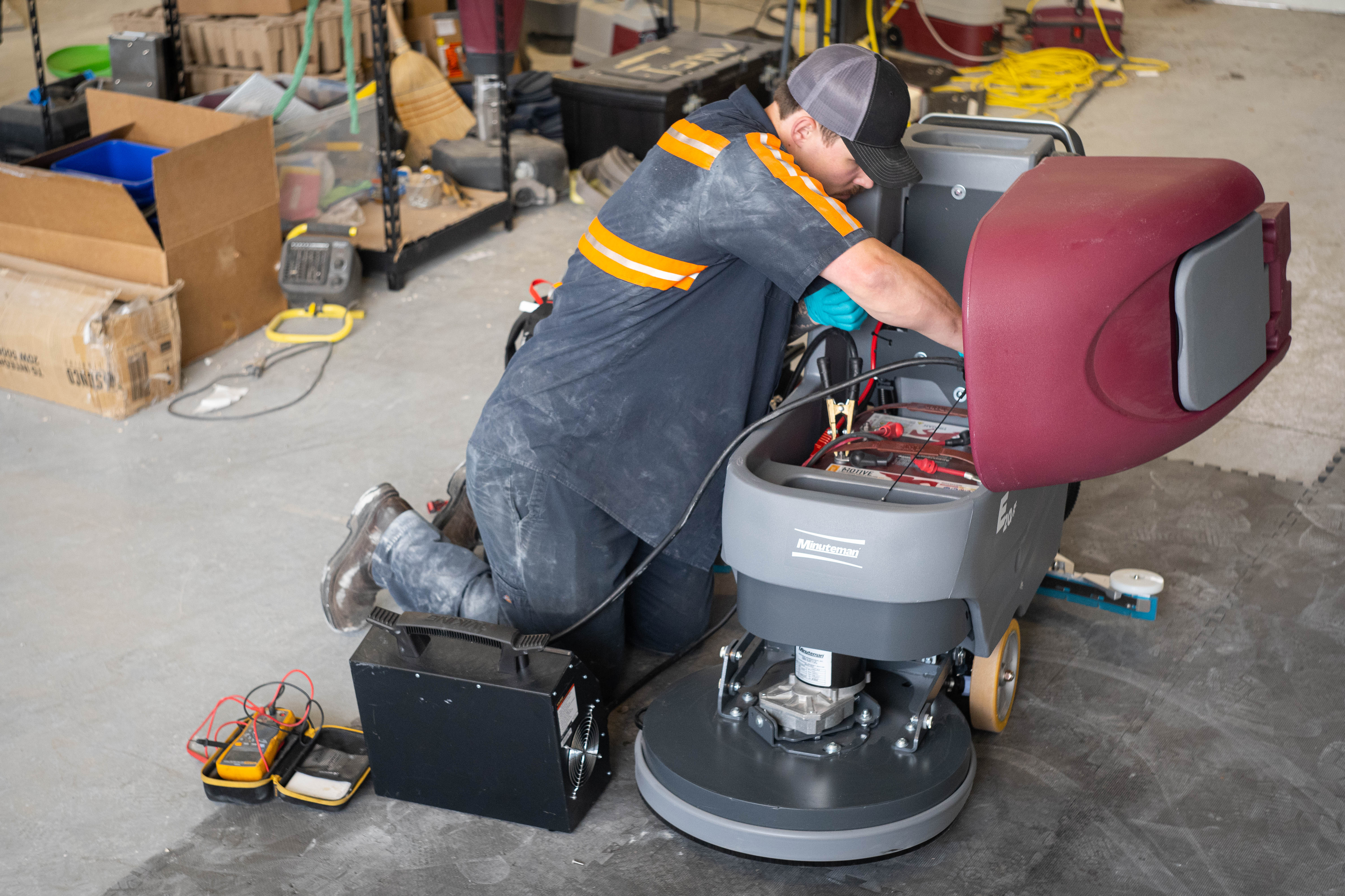 A WaySolutions field technician performs a deep power system overhaul on a Minuteman E20 walk-behind floor scrubber. Using heavy-duty diagnostic equipment, including a Viking load tester and a digital multimeter, our experts in Layton, Utah, ensure your commercial cleaning fleet maintains peak battery performance and reliability.