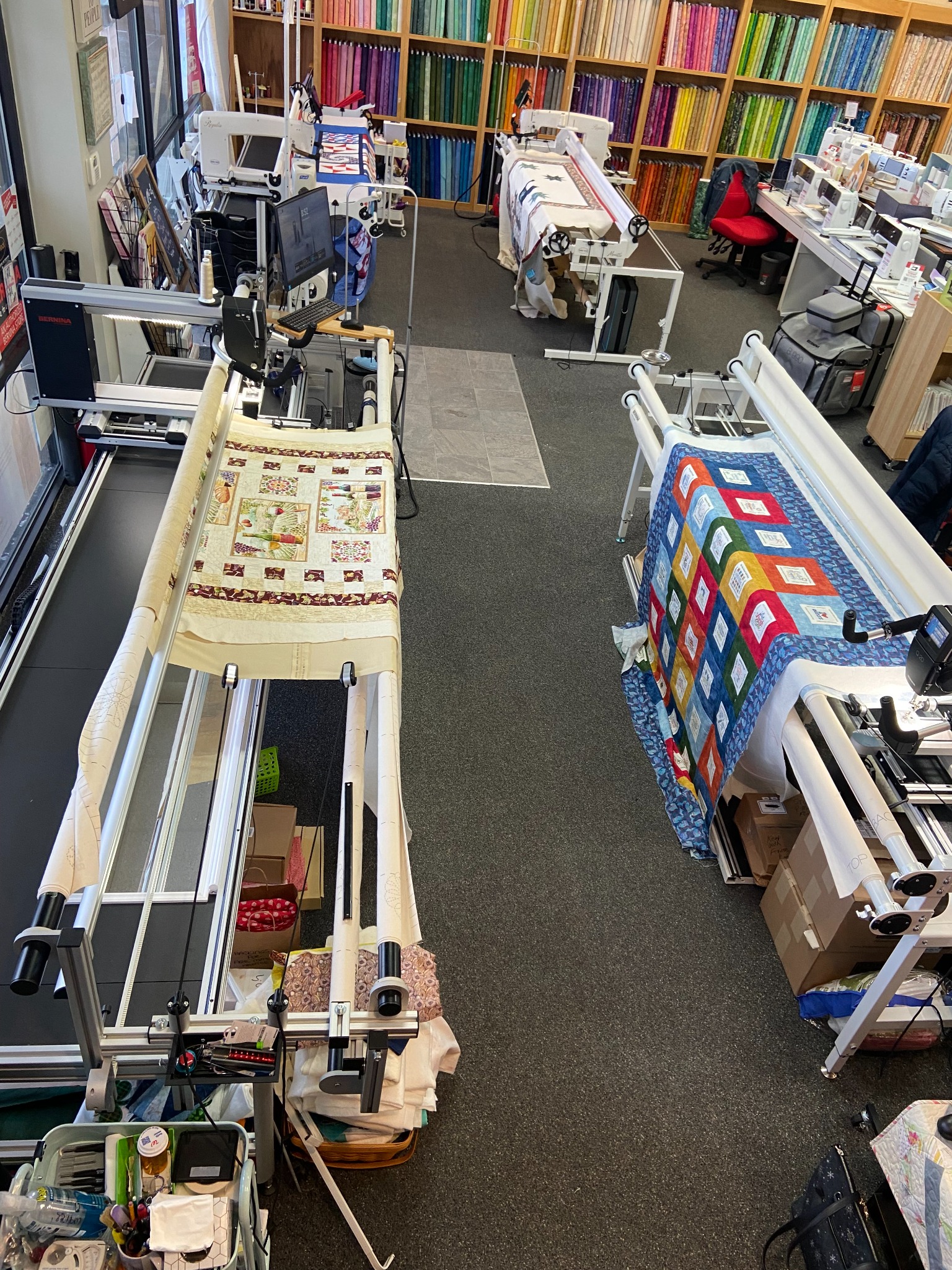 A look inside the Decorative Stitch longarm quilting studio featuring professional quilting machines, colorful fabric displays, and works in progress. The perfect space for precision quilting and creative projects.