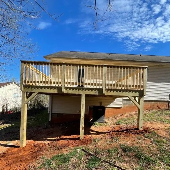 An elevated wooden deck attached to a house, supported by posts.