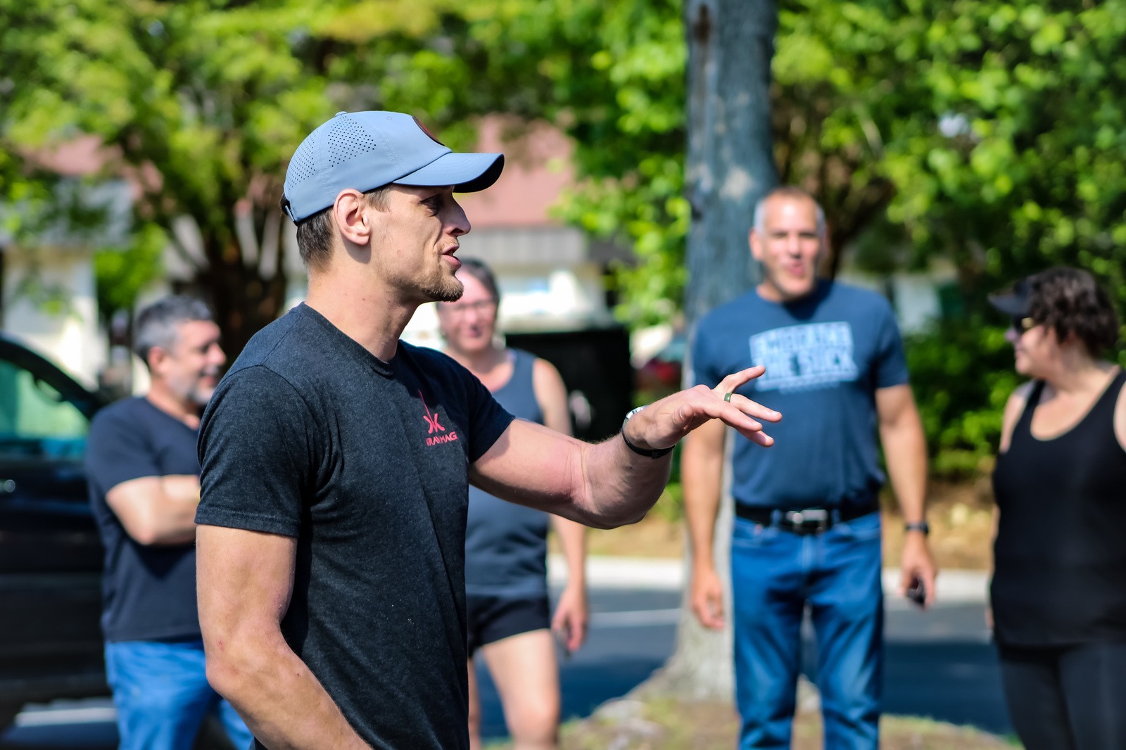 An instructor briefing adult students during an outdoor self-defense class in the lot outside Katalyst Kombatives.