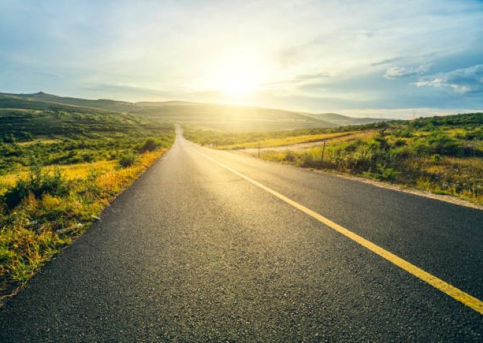 Open road along a sunny scenic route surrounded by rolling hills.