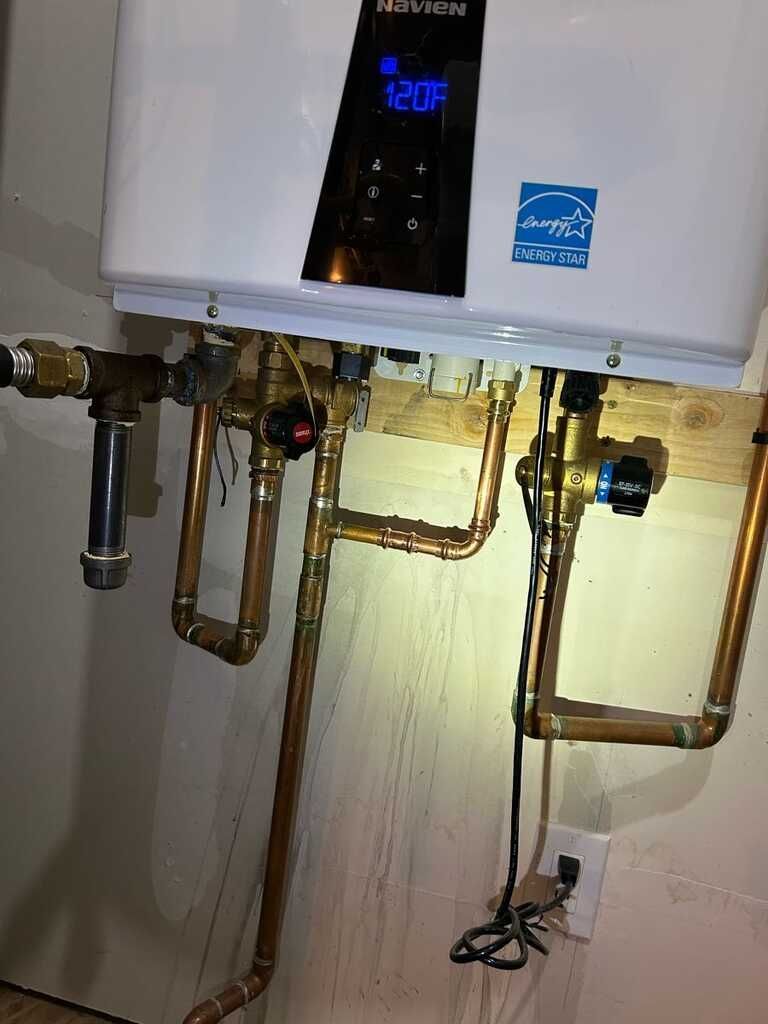 Wall mounted tankless water heater connects to multiple copper water lines, valves, electrical wirin 