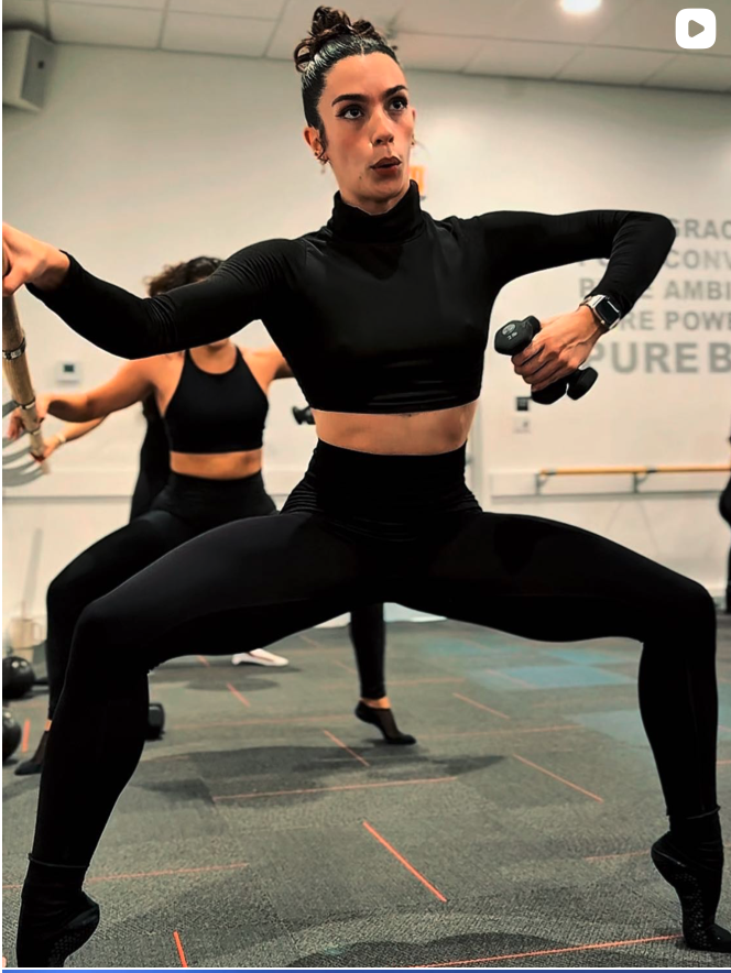 Pure Barre Empower class in Aventura FL — member performing strength and cardio combination exercises with dumbbells at the barre