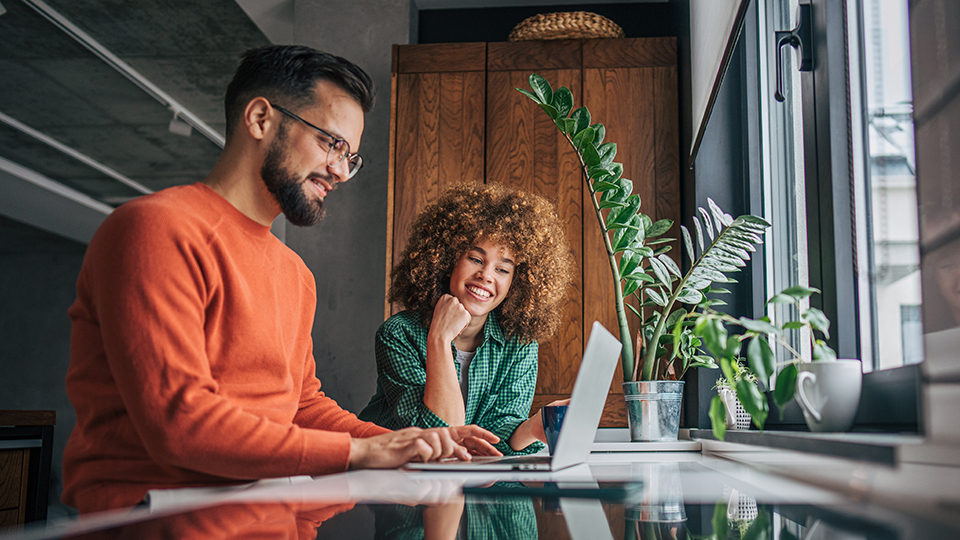 A man and woman looking at an open laptop