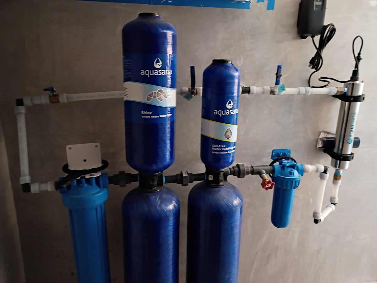 Installed water filtration and treatment system with blue tanks, filters, and plumbing connections for improved home water quality.