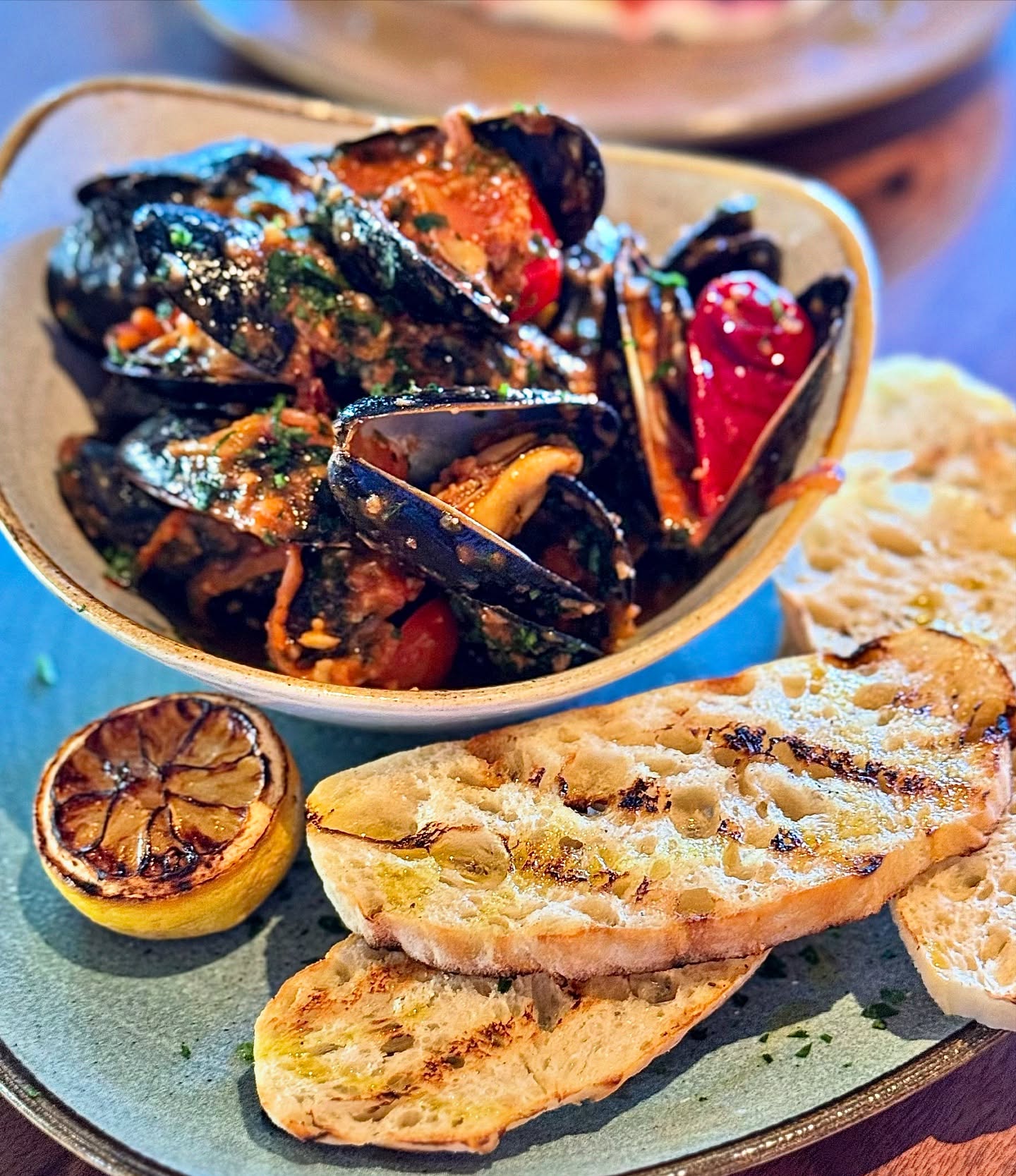 Have you experienced the Prince Edward Island Mussels yet?
These delicate mussels are served in a rich white wine and butter sauce, layered by Calabrian chili peppers, garlic, onion, and tomato.
Finished with grilled ciabatta, because leaving the sauce behind simply isn’t an option.