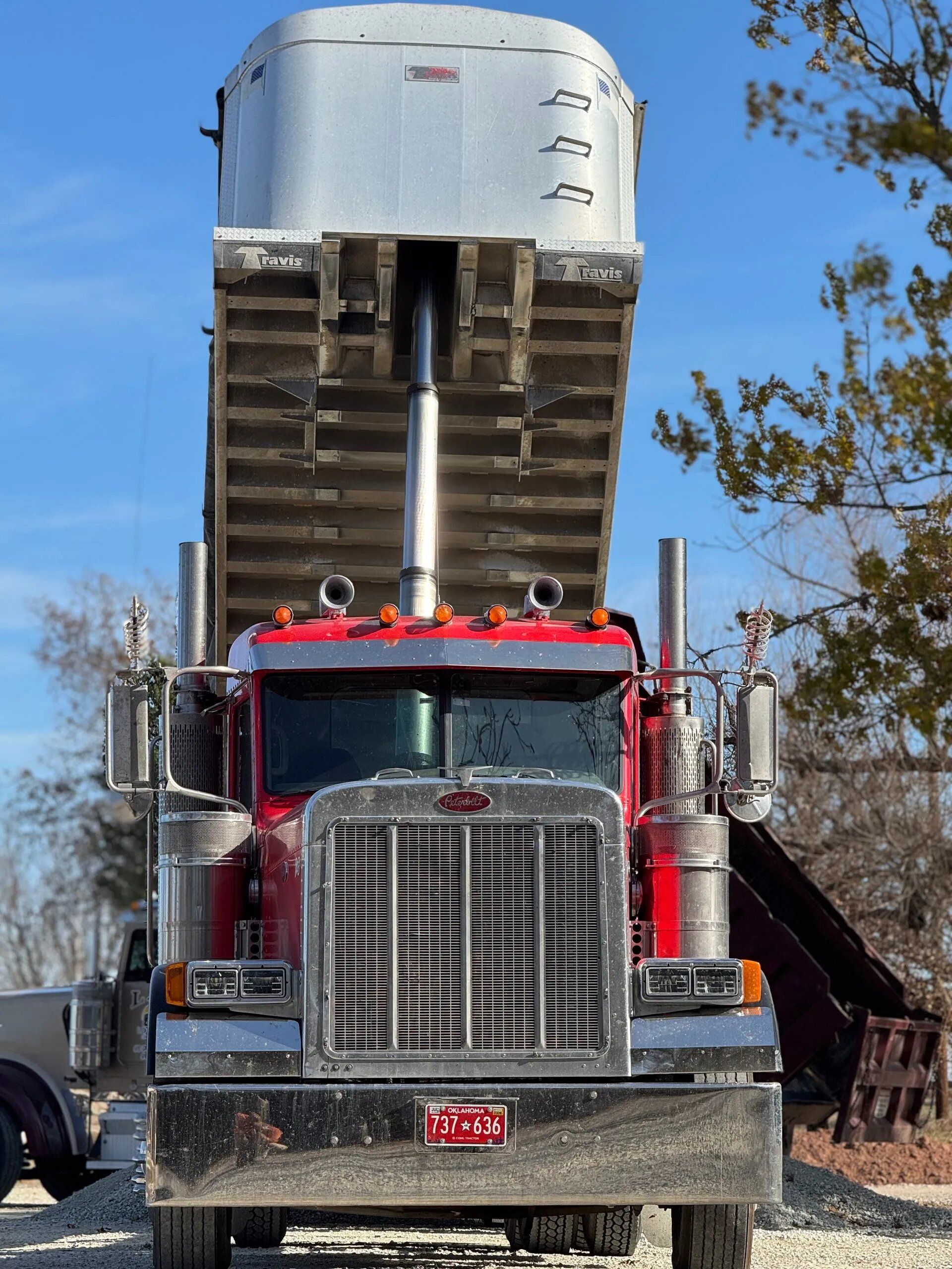 L & R Logistics LLC red dump truck photographed from the front with its bed raised, highlighting heavy-duty equipment, chrome detailing, and commercial hauling capabilities for Oklahoma projects in Shawnee.