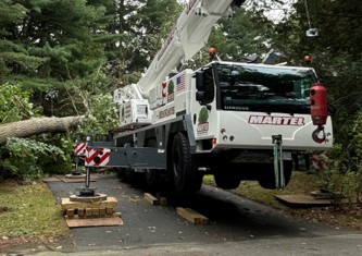 Martel Crane Service & Tree Removal setup in the driveway to remove trees from the yard of this property in Chelmsford, MA.