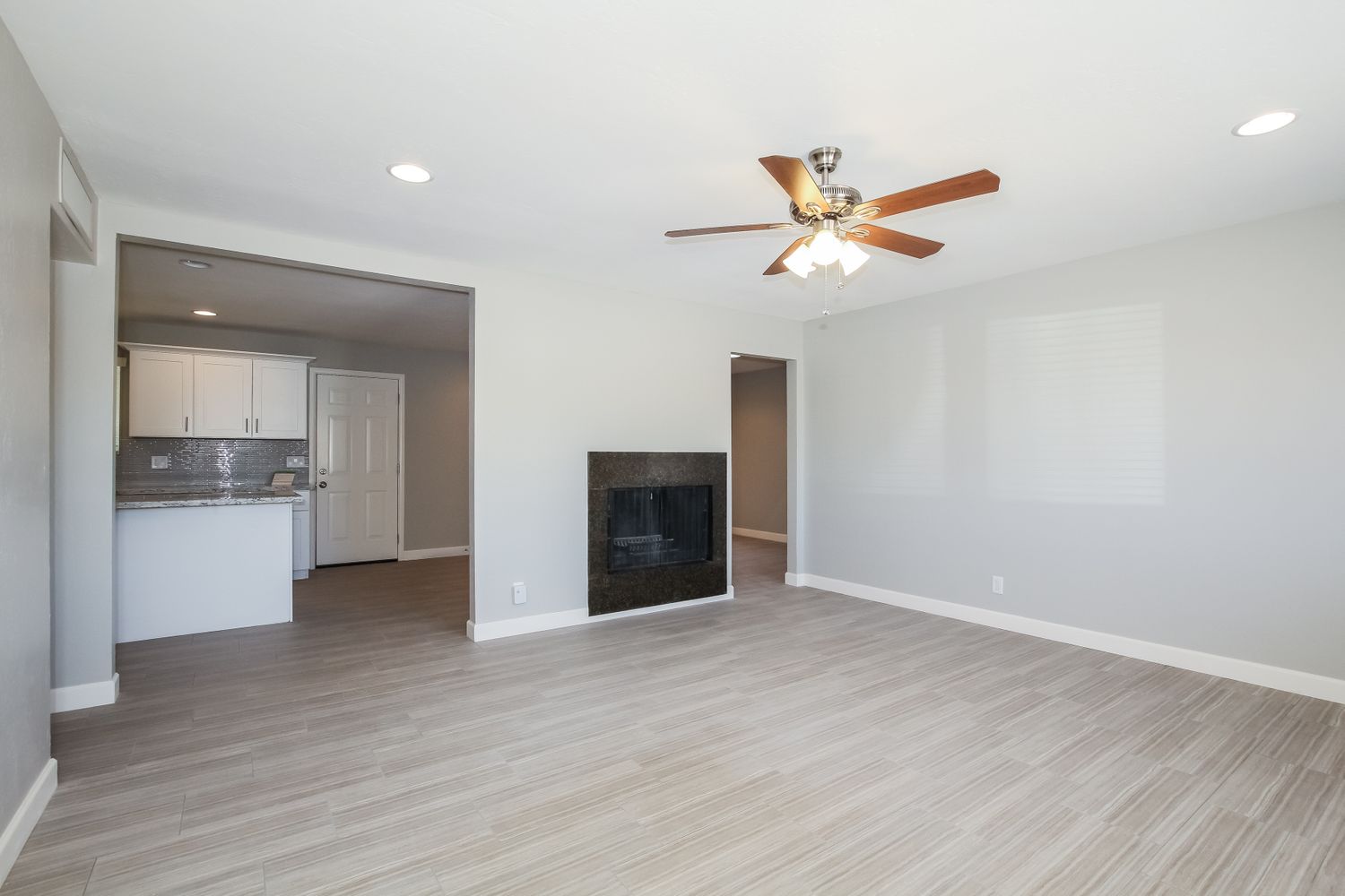 Cozy family room with a fireplace and ceiling fan at Invitation Homes Phoenix.