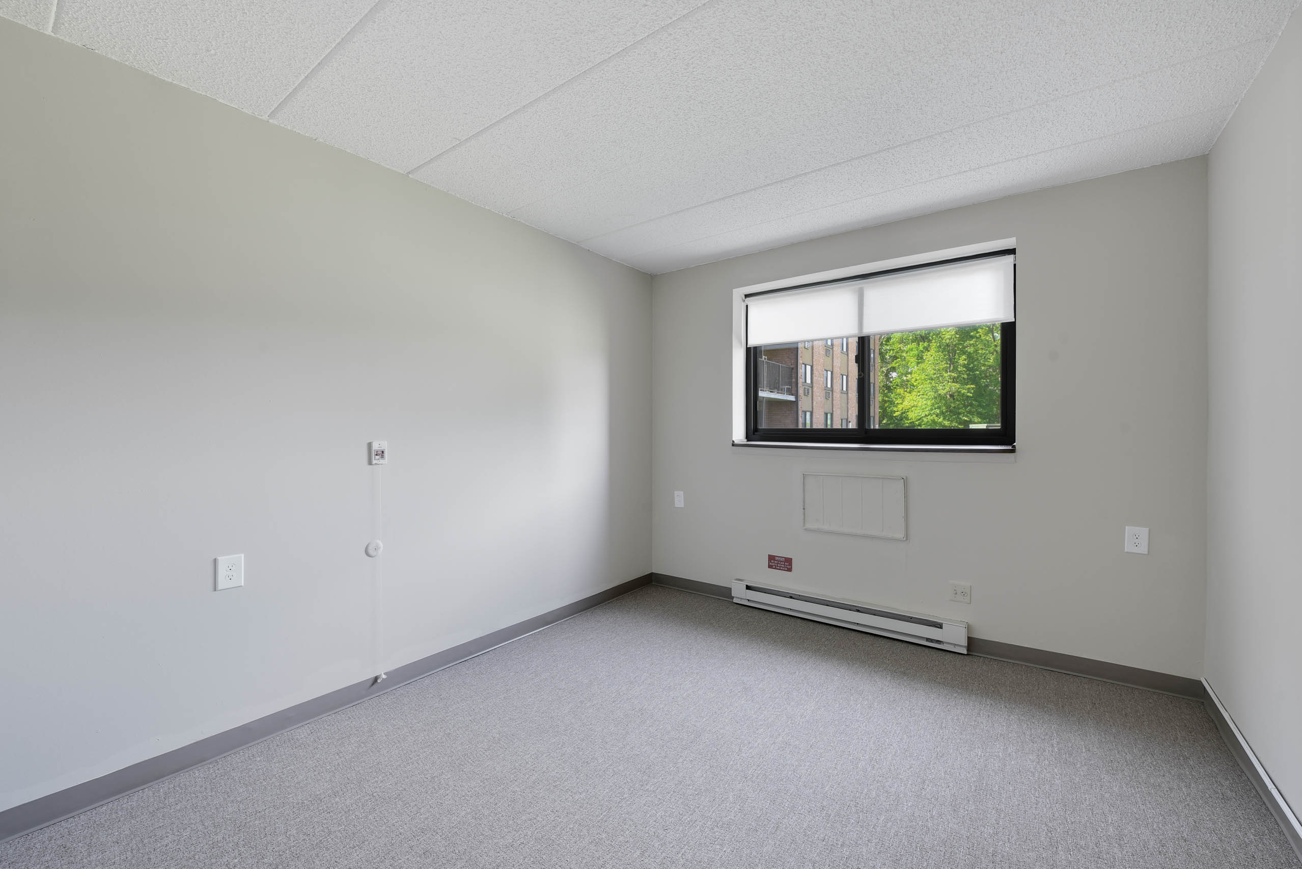 A room with a window and a carpeted floor.