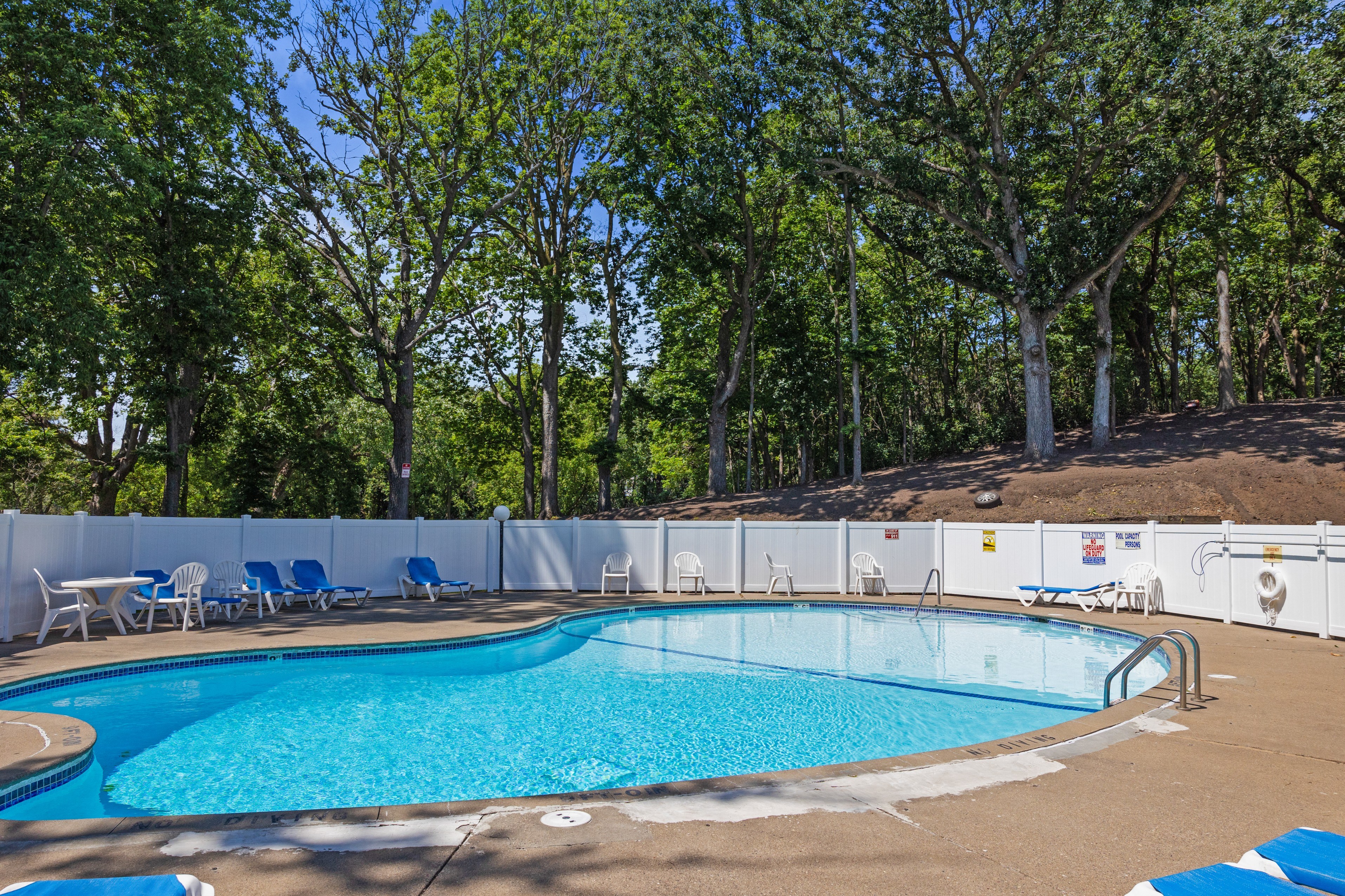 a swimming pool with chairs around it and trees in the background at Heritage Hills Apartments, Minnesota, 55437