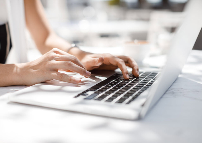 Closeup of a person typing on their laptop.