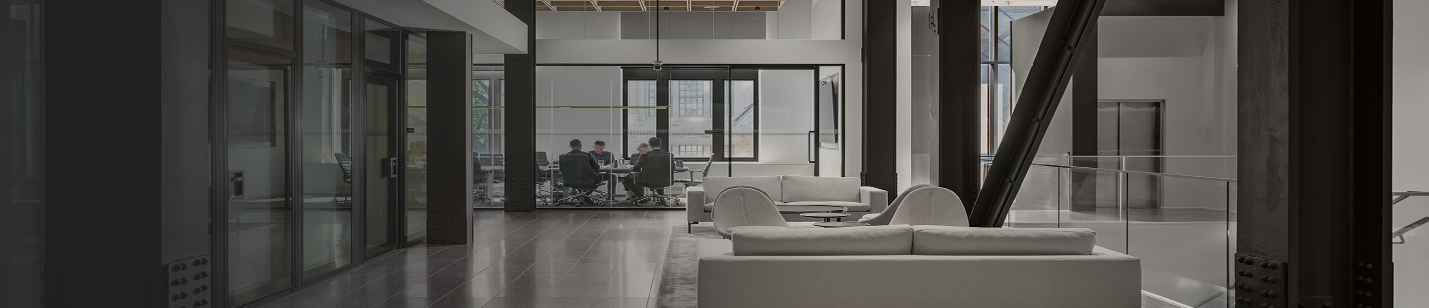 Lounge area in the Ascendant Wealth Partners office with a view of four colleagues meeting in a glass-walled conference room.