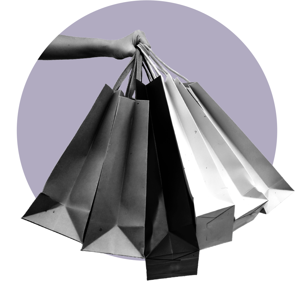 Partial view of a person's arm extended while holding a handful of paper shopping bags on top of a purple circle.