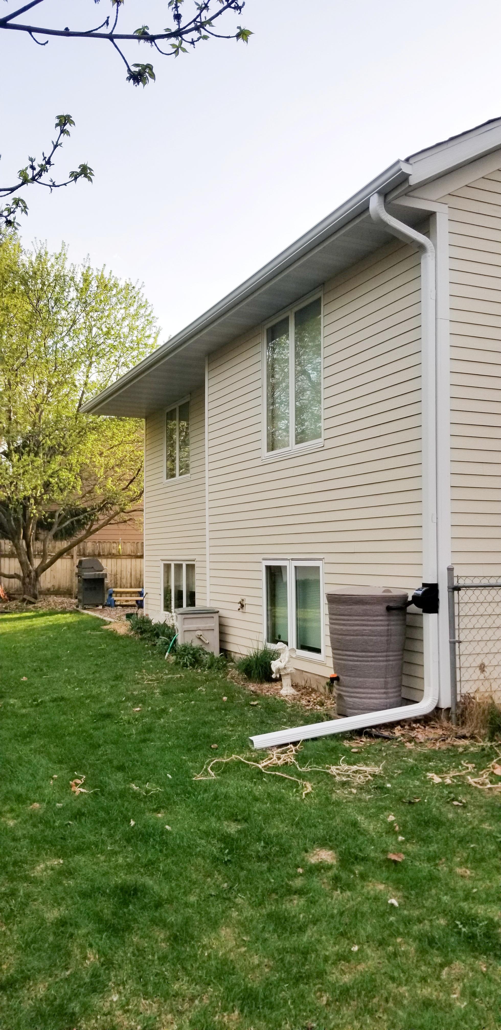 White seamless gutters and a downspout system installed on a residential home by Ultimate Gutter Solutions.