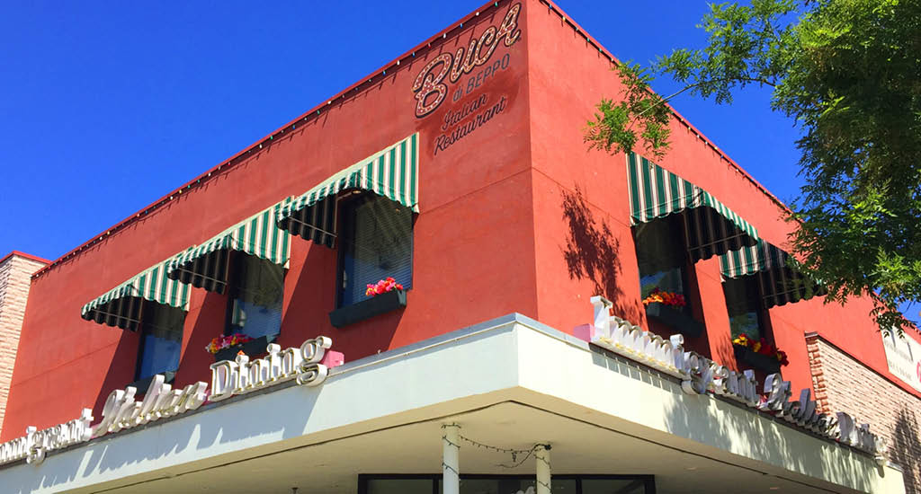 Second-floor green and white striped windows with Italian Dining sign on red building at Buca di Beppo Salt Lake City.