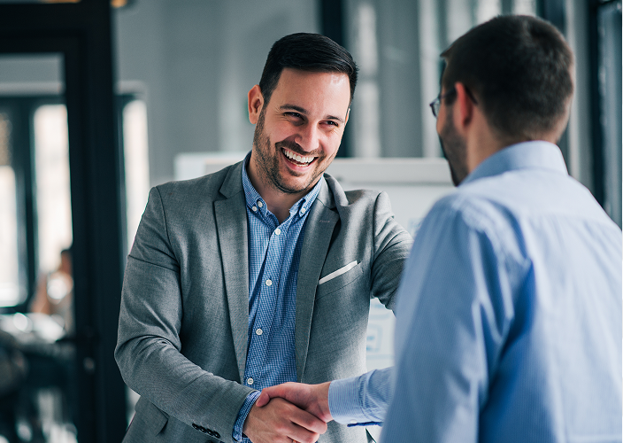 Businessmen shaking hands in an office setting.
