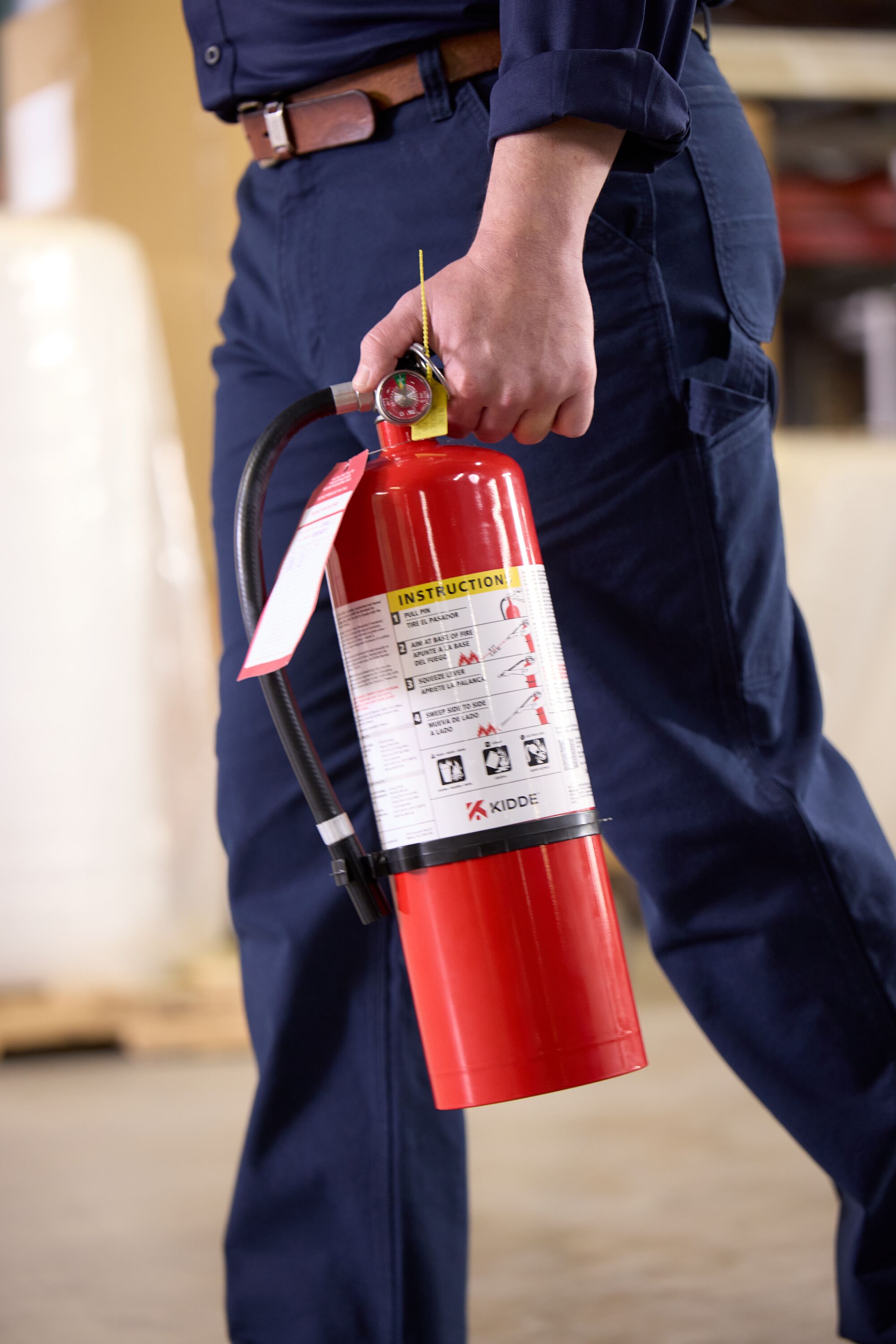 Image of a person carrying a commercial fire extinguisher.