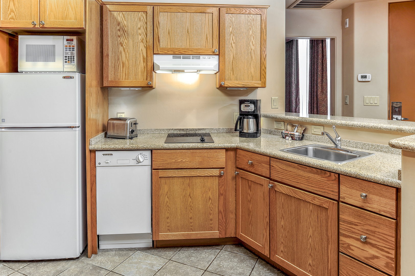 A kitchen in an accommodation at Bell Rock Inn. It's equipped with a full-size refrigerator, microwave, dishwasher, coffeemaker, toaster, stovetop, and sink.