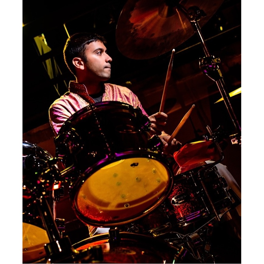 An electrifying performance brought to life by WS Event Production Inc.'s expert lighting design. The dynamic combination of vibrant purple and golden hues reflects off the drum kit, highlighting the energy and passion of the drummer. The focused spotlight enhances the musician's presence on stage, creating a captivating visual experience for the audience while ensuring every beat resonates with power and rhythm.