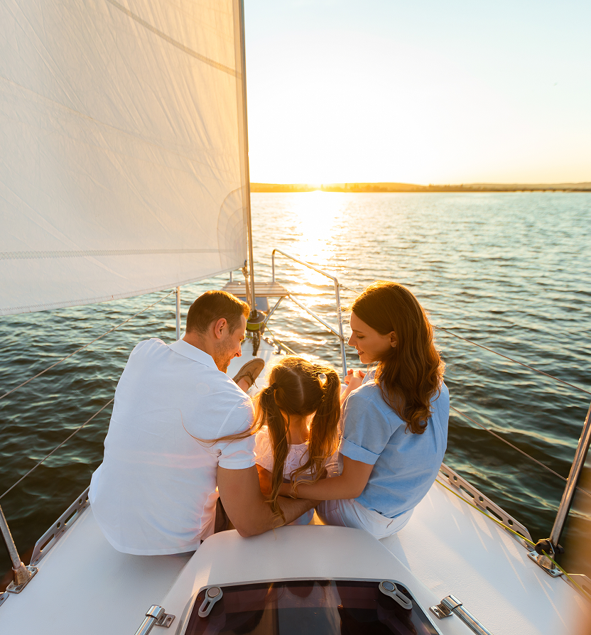 Parents and their child enjoying the sunset on a sailboat.
