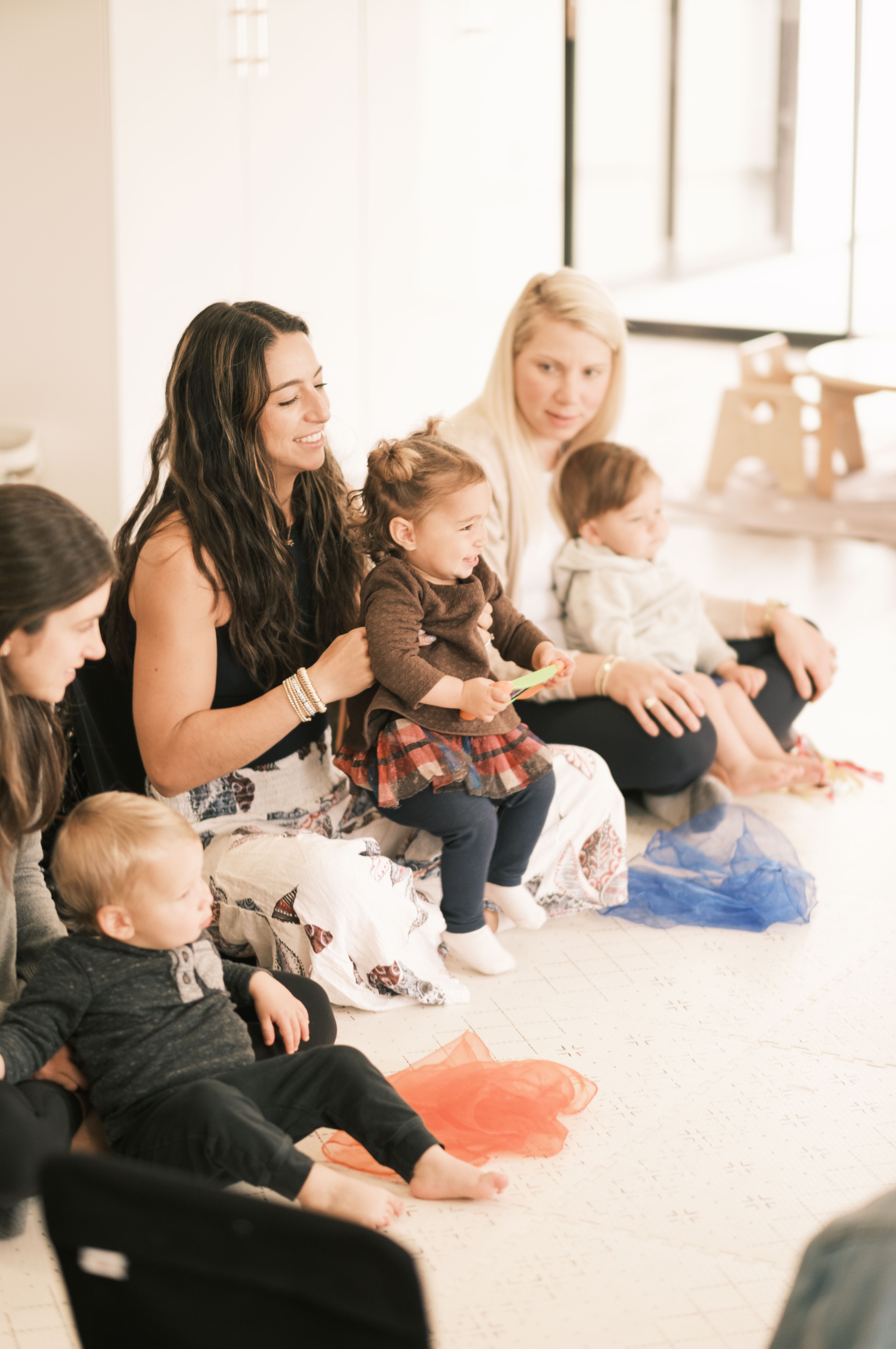 Three moms sit in a row with their babies facing the instructor