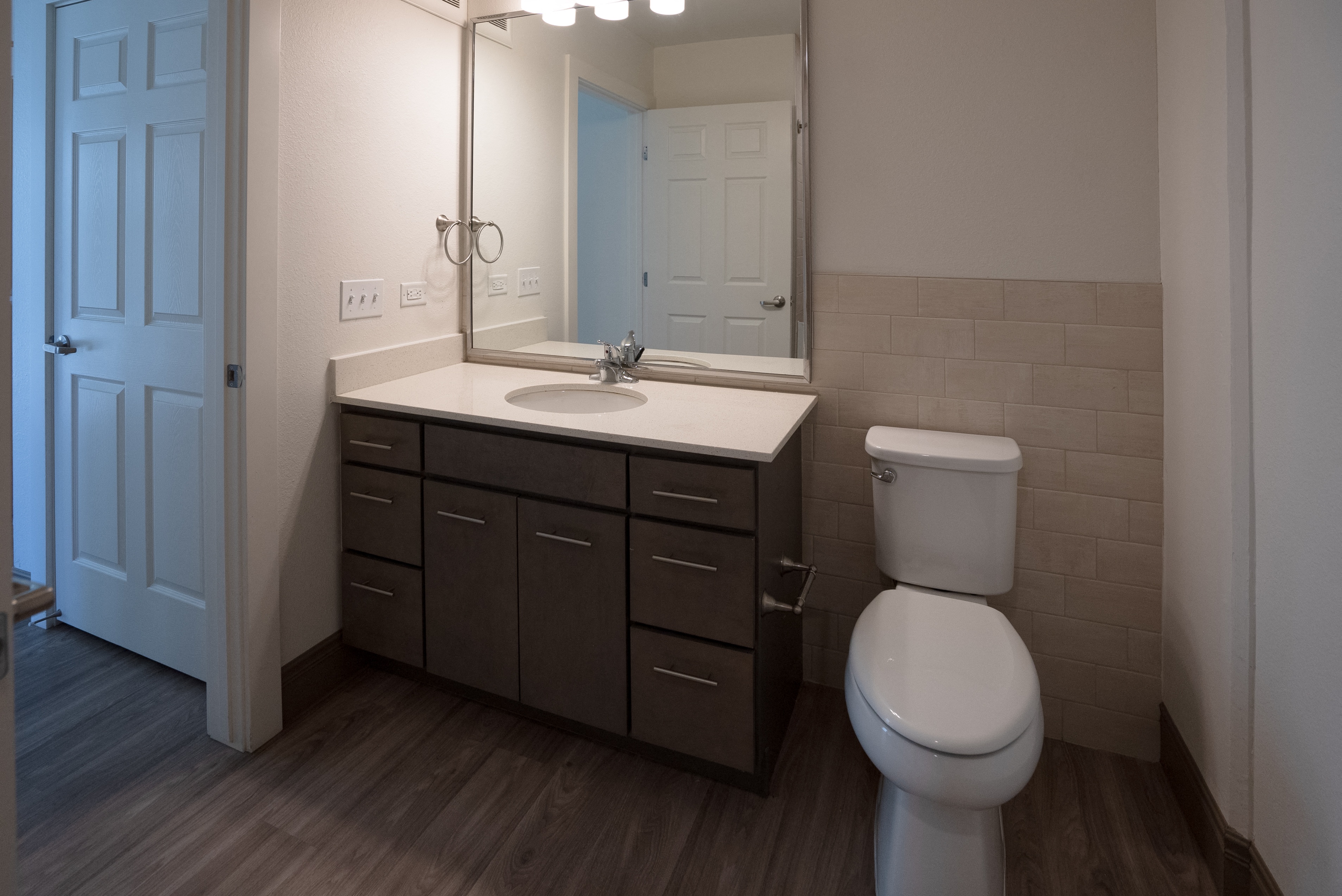 A bathroom with a toilet, sink, and mirror.